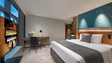 A modern hotel room with a large bed, a desk, and a piano.