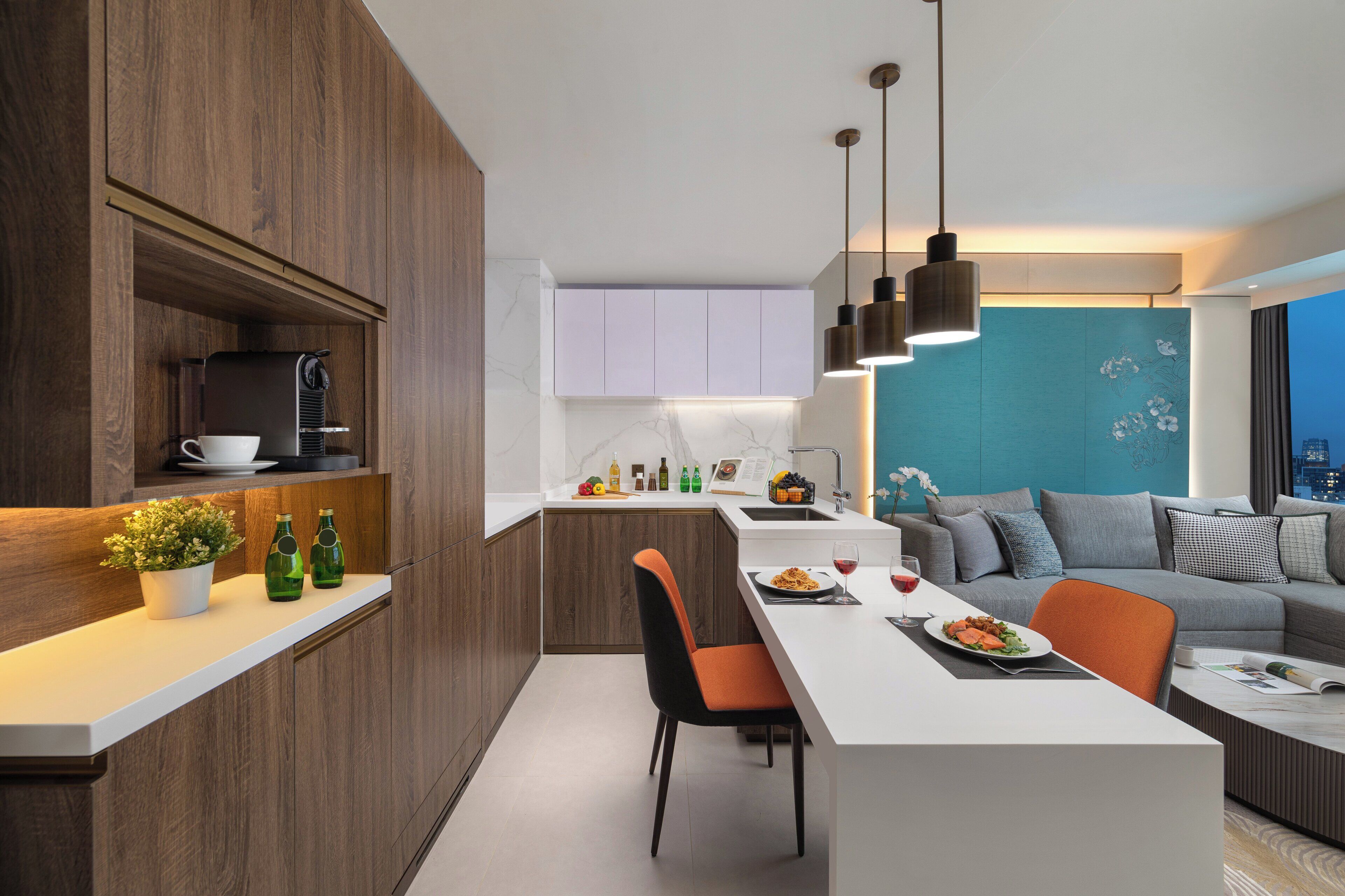 Eine moderne Küche mit Holzausstattung, einer weißen Arbeitsplatte und einem Essbereich mit weißem Tisch und orangefarbenen Stühlen.