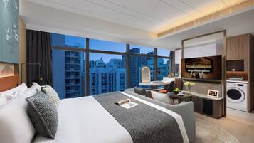 Ein modernes Hotelzimmer mit einem großen Bett, einem Schreibtisch, einer Waschmaschine und Blick auf die Stadt.