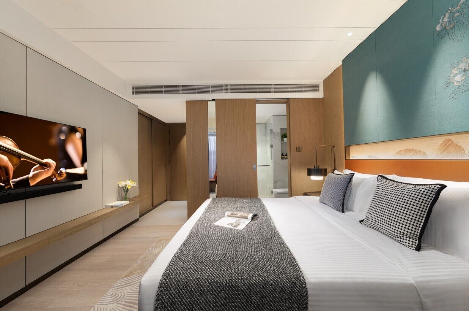 Ein modernes Hotelzimmer mit einem großen Bett, einem Flachbildfernseher und Blick ins Badezimmer.