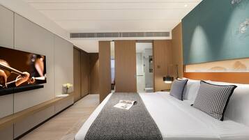 Ein modernes Hotelzimmer mit einem großen Bett, einem Flachbildfernseher und Blick ins Badezimmer.