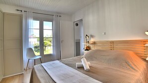 A bedroom with a large bed, a chair, a desk, and a window with curtains. - Stunning private villa for 6 people with WIFI, pool and TV (La Cotinière)