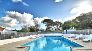 A rectangular swimming pool with a tiled deck, surrounded by white lounge chairs and a wooden fence. - Stunning private villa for 6 people with WIFI, pool and TV (La Cotinière)