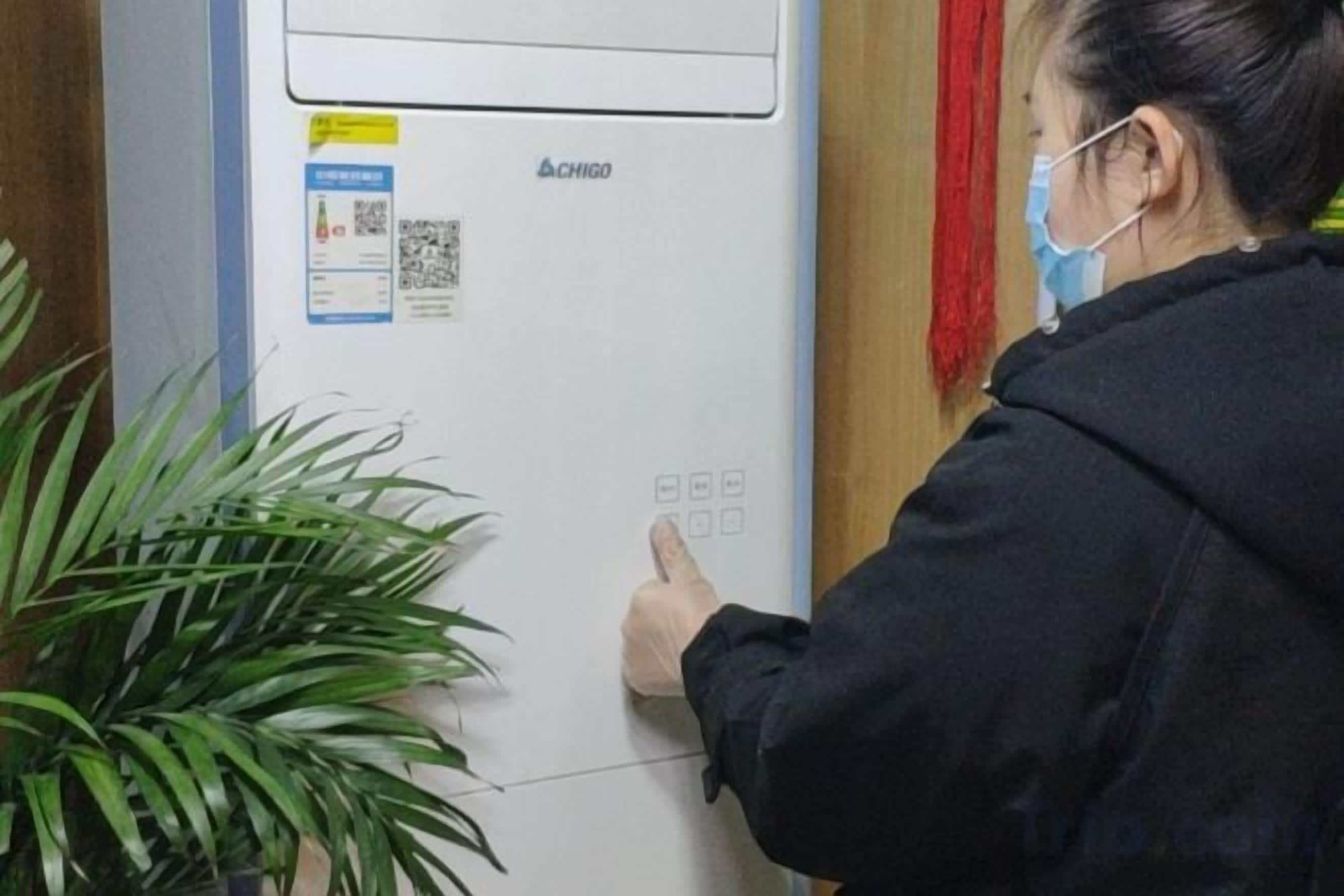 A person interacting with a control panel on a wall-mounted device, possibly for room temperature or lighting.