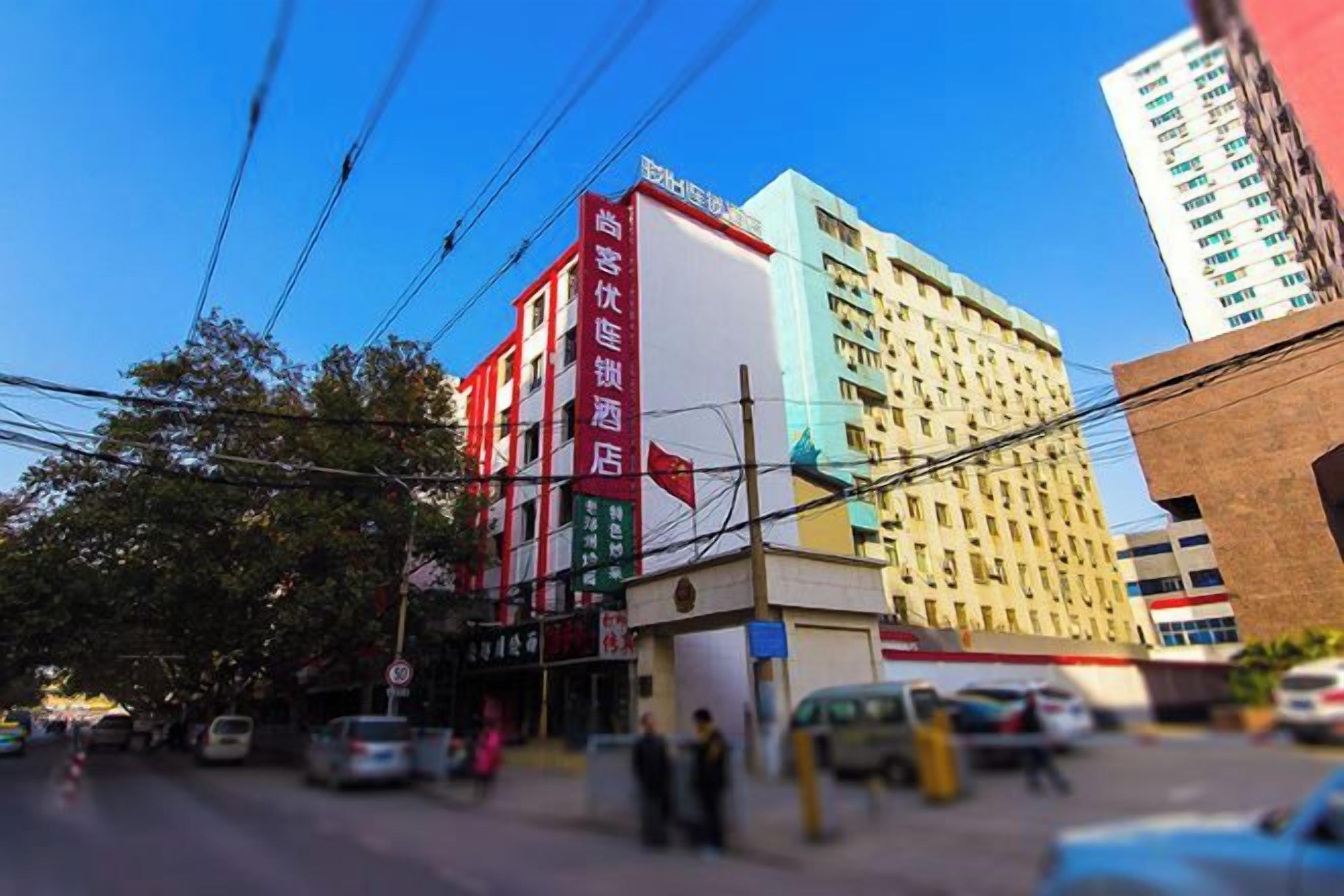 A multi-story building with a red and white facade, a visible sign, and a clear sky.