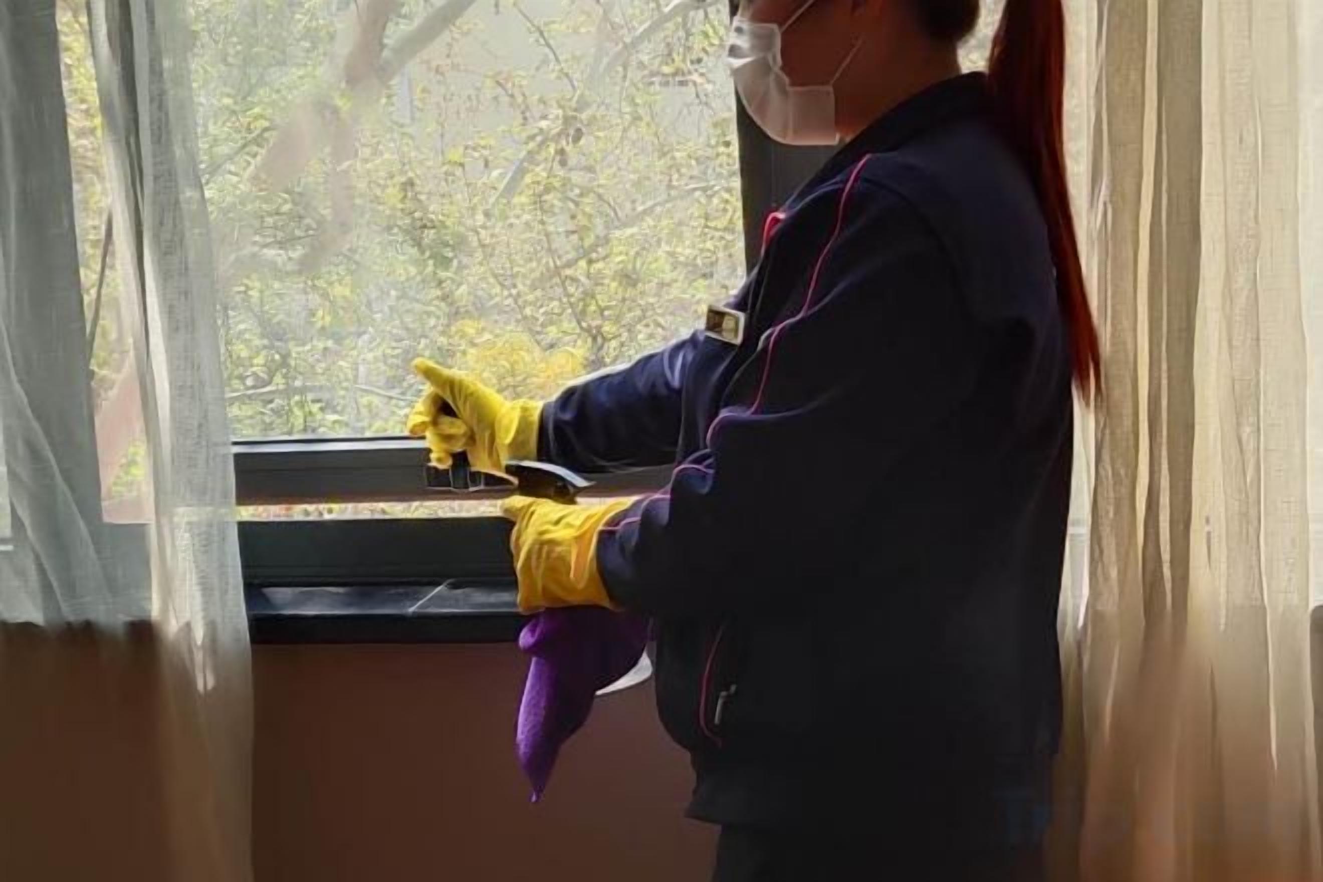 A person cleaning a window with a cloth and a spray bottle.