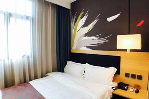 Une chambre d’hôtel avec un lit, une table de chevet avec un téléphone, une lampe et un mur orné d’un motif de feuilles.