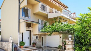 Un edificio residenziale a due piani con un balcone, un garage e una facciata in pietra.