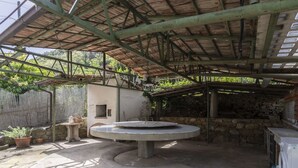 A covered outdoor area with a circular concrete table, stone walls, and a washing machine. - Wonderful private villa for 3 guests with WIFI, TV, terrace, pets allowed and panoramic view (Castellaro)