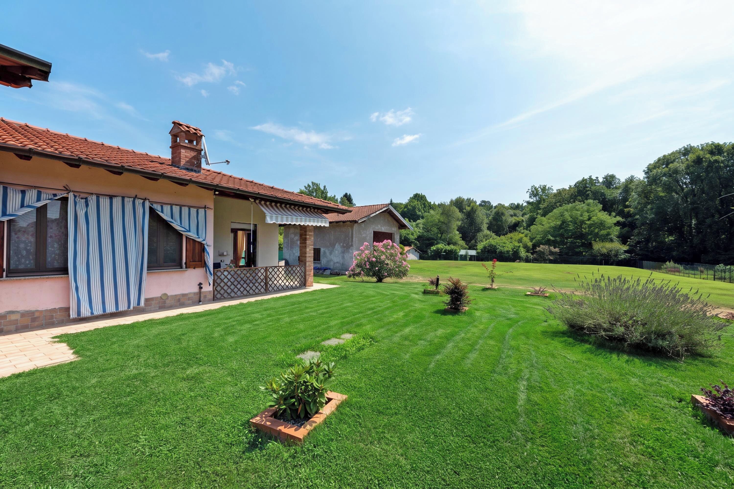 Ein Haus mit gepflegtem Rasen, einem kleinen Garten und blauem Himmel.