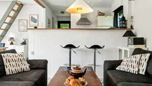 A cozy living room with two dark sofas, a wooden coffee table with pastries, a hanging lamp, and a ladder against the wall. - "Laerke" - 200m from the sea by Interhome (Gudhjem)