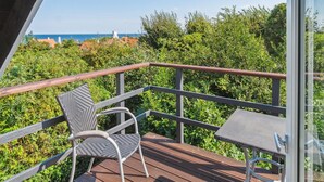 A balcony with a wicker chair and a small table, overlooking a lush green landscape and the sea. - "Laerke" - 200m from the sea by Interhome (Gudhjem)