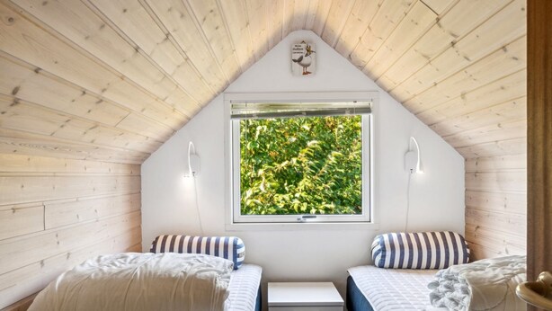 A cozy attic bedroom with two beds, a window with a view of greenery, and a small bedside table. - "Laerke" - 200m from the sea by Interhome (Gudhjem)