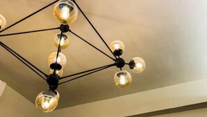 Un luminaire de plafond composé de plusieurs ampoules sphériques reliées par des tiges noires.
