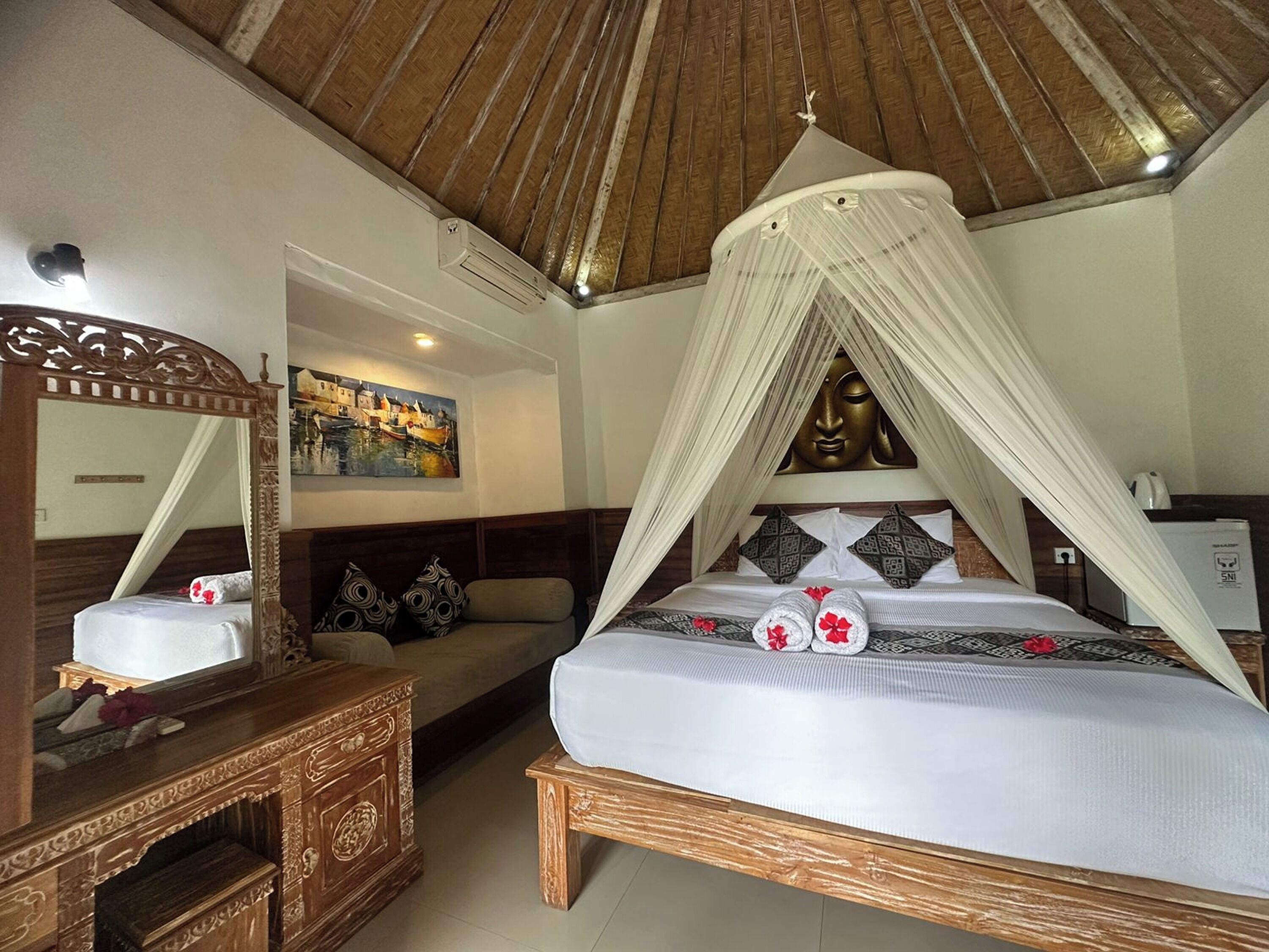 Ein Schlafzimmer mit Himmelbett, einem hölzernen Schminktisch, einem Spiegel, einem Gemälde und einem Deckenventilator.