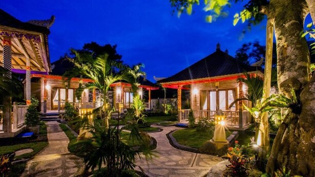 Un edificio de estilo tradicional con techo de paja, rodeado de jardines y senderos bien cuidados.