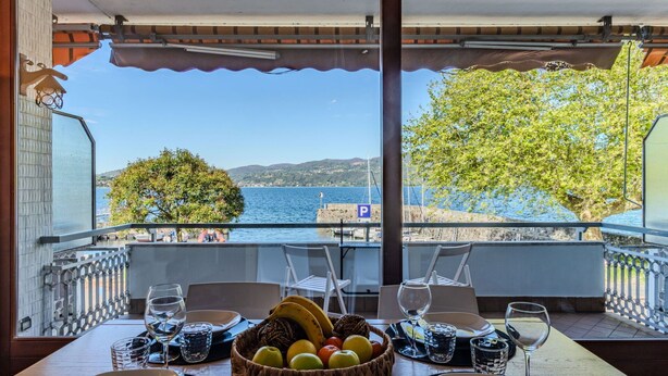 A dining table set for two with a view of the sea and a parking sign in the background. - Lovely apartment for 4 guests with WIFI, A/C, TV and terrace (Ispra)