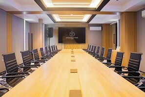 A conference room with a long table, chairs, a screen, and a logo on the wall.