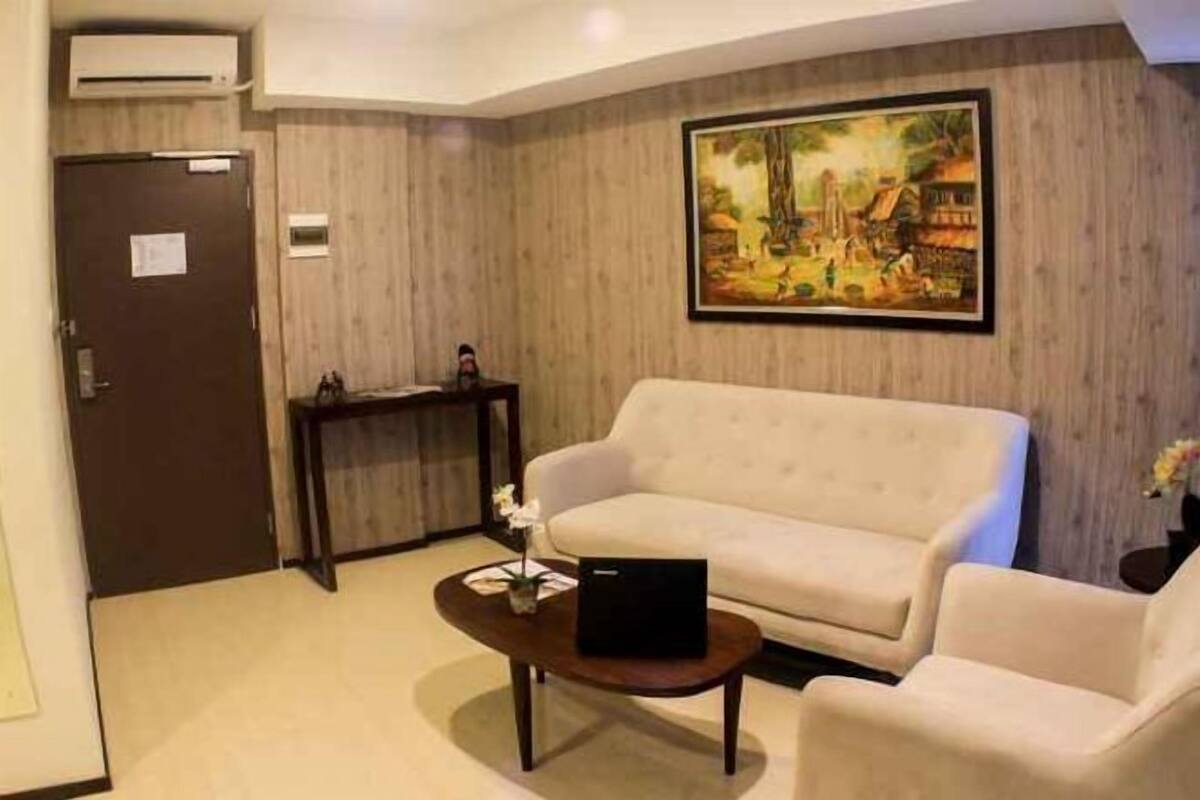 Una sala de estar con un sofá color beige, una mesita de centro y un cuadro en la pared.