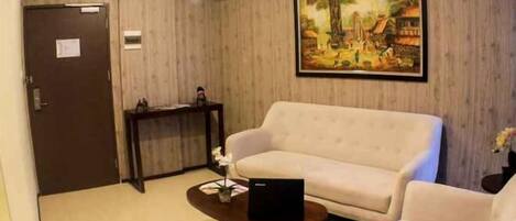 Una sala de estar con un sofá color beige, una mesita de centro y un cuadro en la pared.