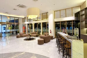 A spacious lobby with a bar area, seating arrangements, and large windows.