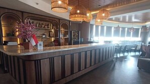 A bar area with a wooden counter, hanging wicker lamps, and a view of the dining area. - Kebayoran Park Hotel (South Jakarta)