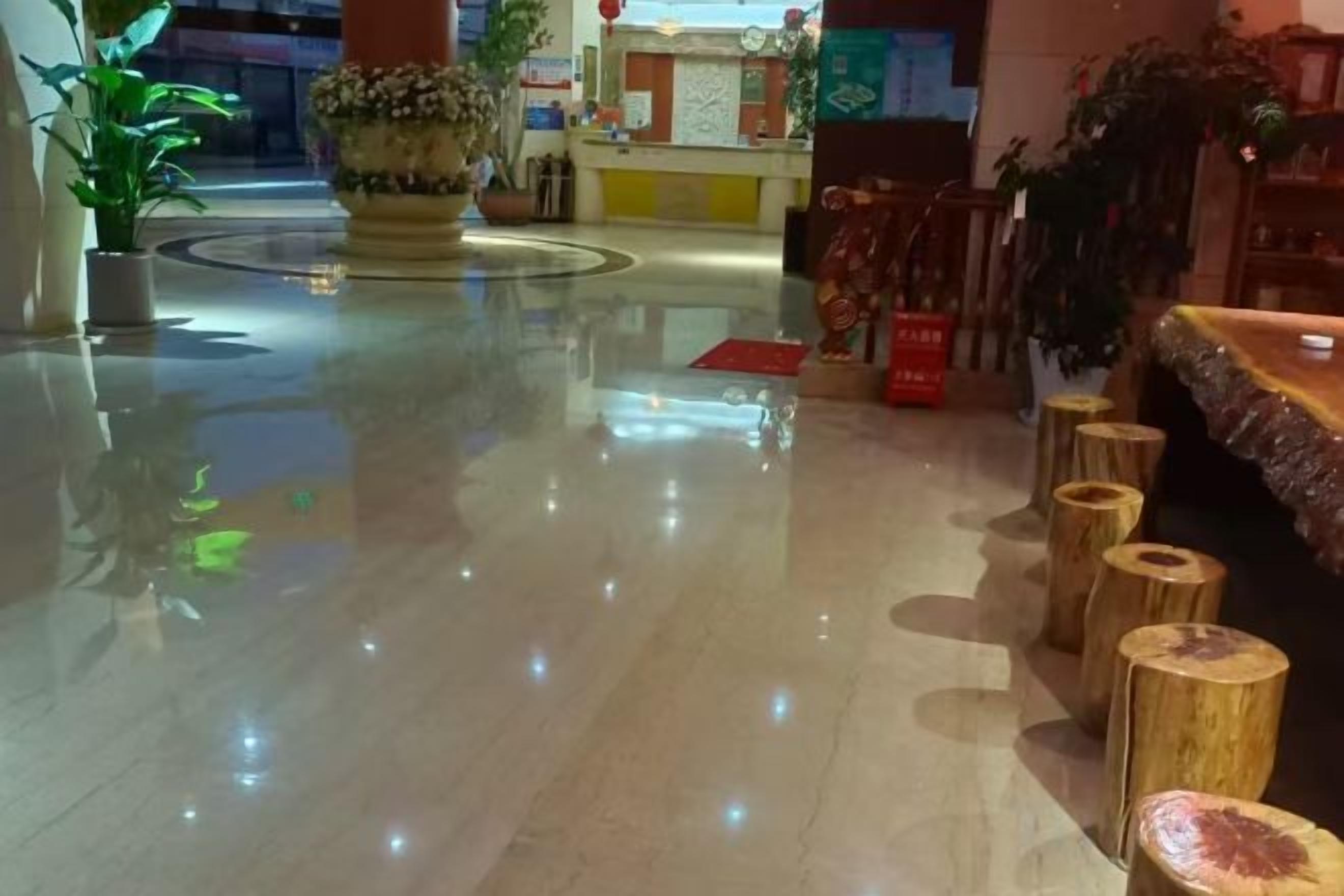 A polished lobby with a reception desk, potted plants, and a wooden bench area.
