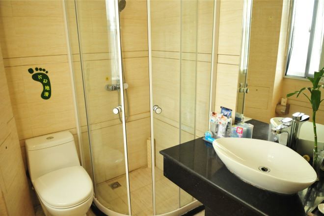 Une salle de bain comprenant des toilettes, une douche fermée par une paroi de verre et un lavabo avec un miroir au-dessus.