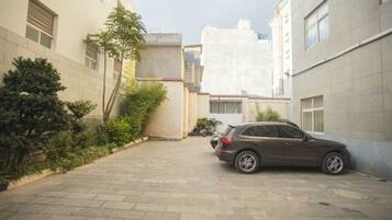 A paved courtyard with a parked car, surrounded by buildings with windows and doors.