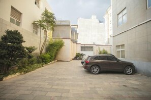 A paved courtyard with a parked car, surrounded by buildings with windows and doors. - Shenzhou Hotel (Xiangyun)