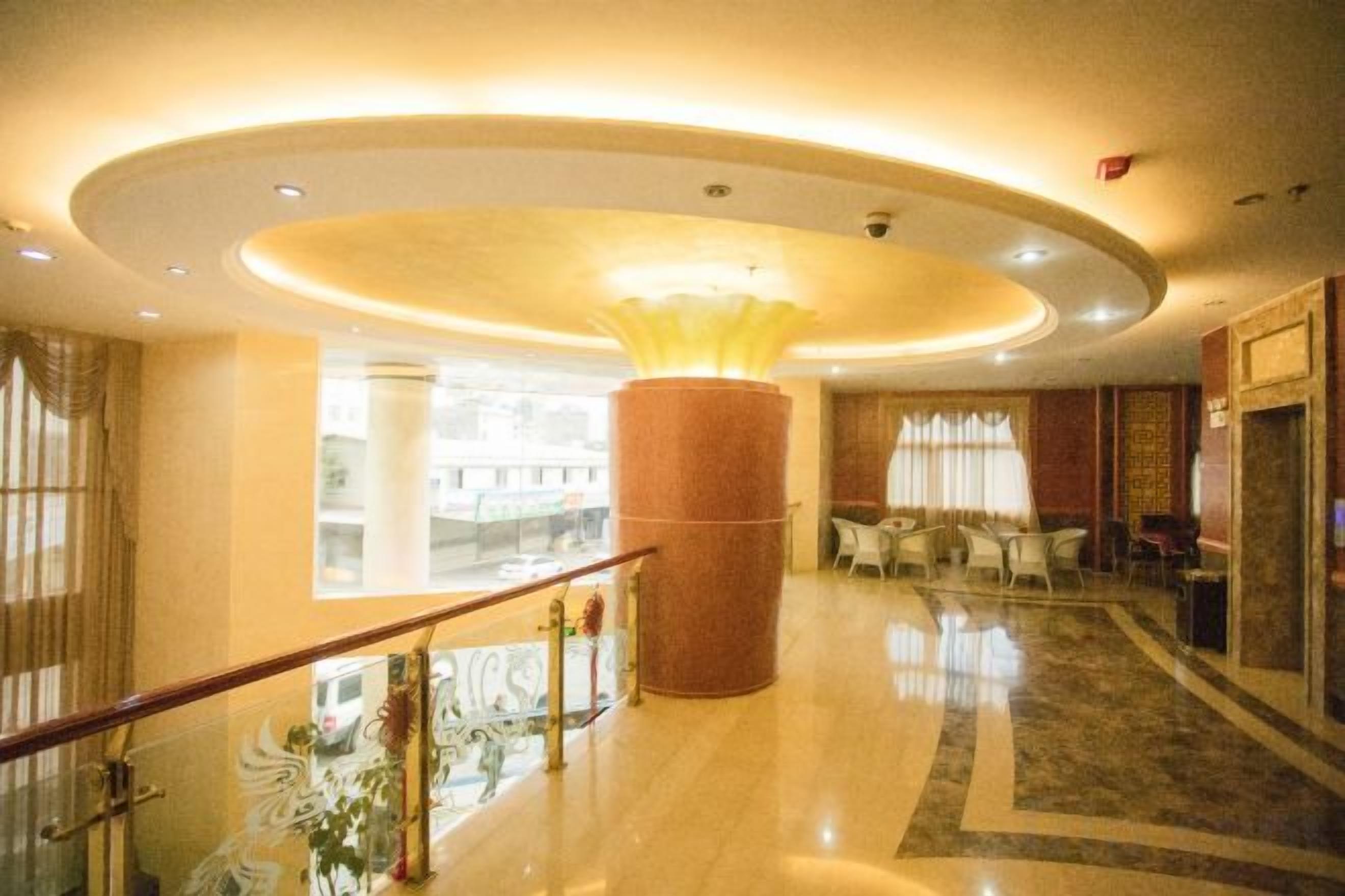 A hotel lobby with a central column, seating area, and a staircase.