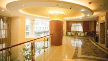 A hotel lobby with a central column, seating area, and a staircase.