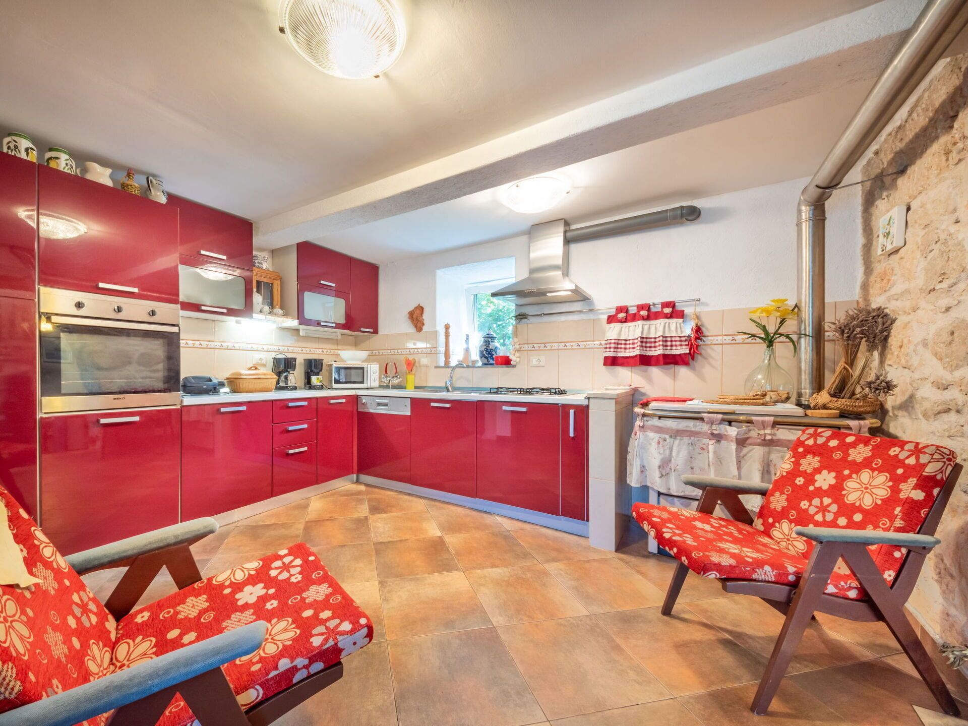 Una cocina con armarios rojos, una estufa y una zona de comedor con mesa y sillas.
