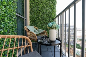 A balcony with wicker chairs, a small table, and a vase of flowers. - Modern 1BR Dania 1 Apartment with Private Balcony (Dubai)