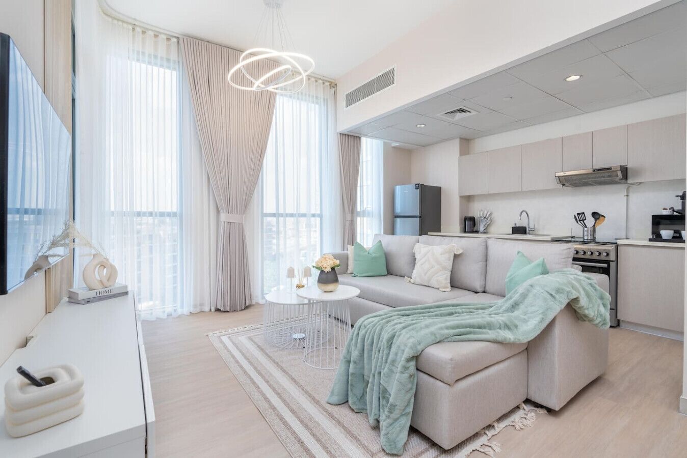 Ein modernes Wohnzimmer mit einer Couch, einem Couchtisch und einem Essbereich, im Hintergrund eine Küche.