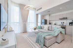 Een moderne woonkamer met een bank, een salontafel en een eethoek, met een keuken op de achtergrond.