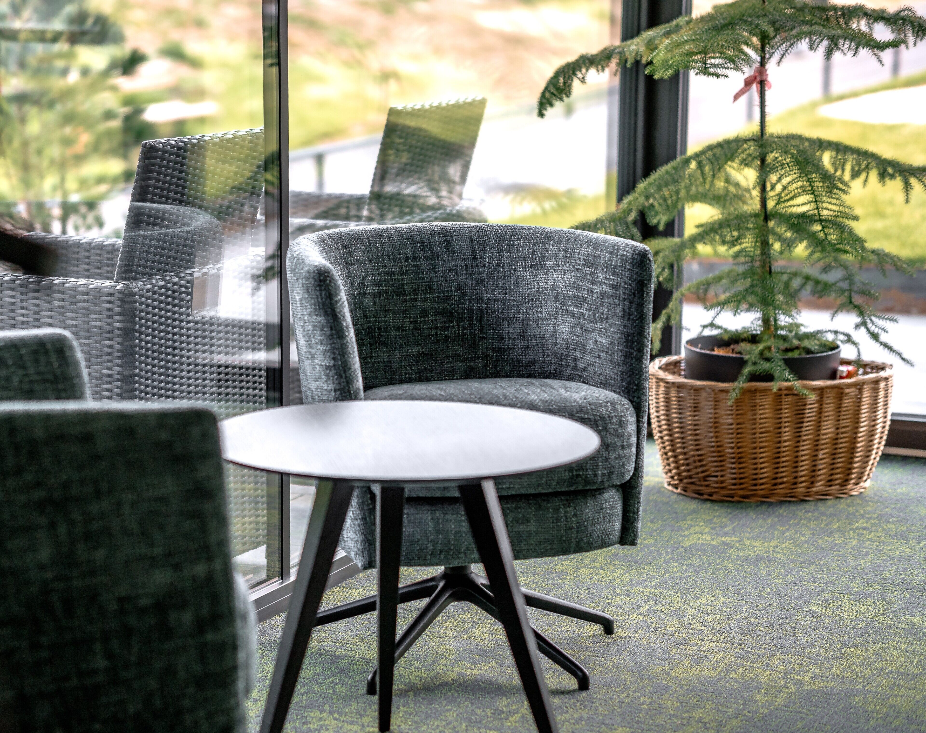 A seating area with a round table, grey woven chairs, and a potted plant.