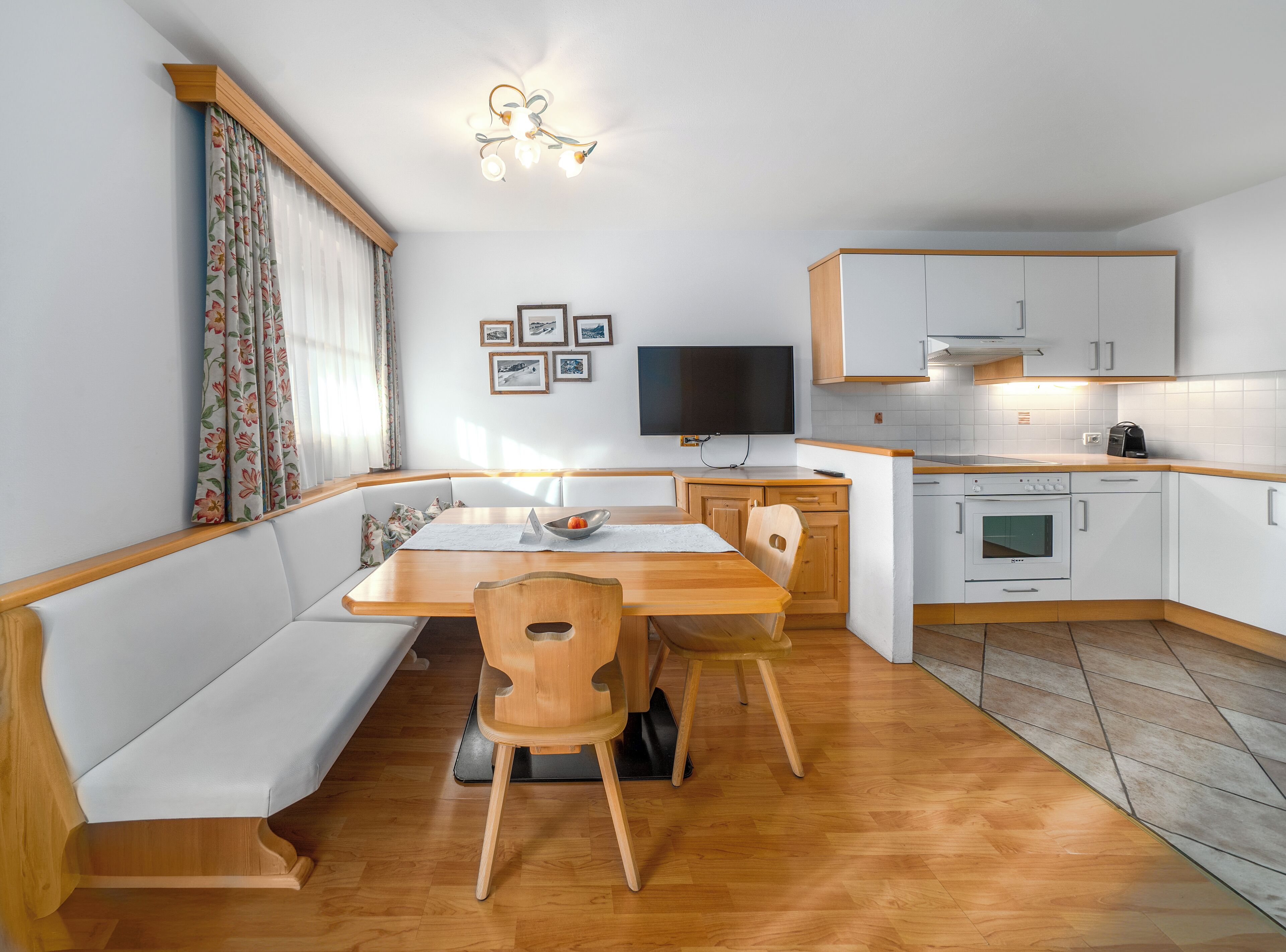 Una cocina compacta con comedor, banca de madera y horno empotrado.