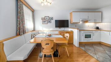 Una cocina compacta con comedor, banca de madera y horno empotrado.