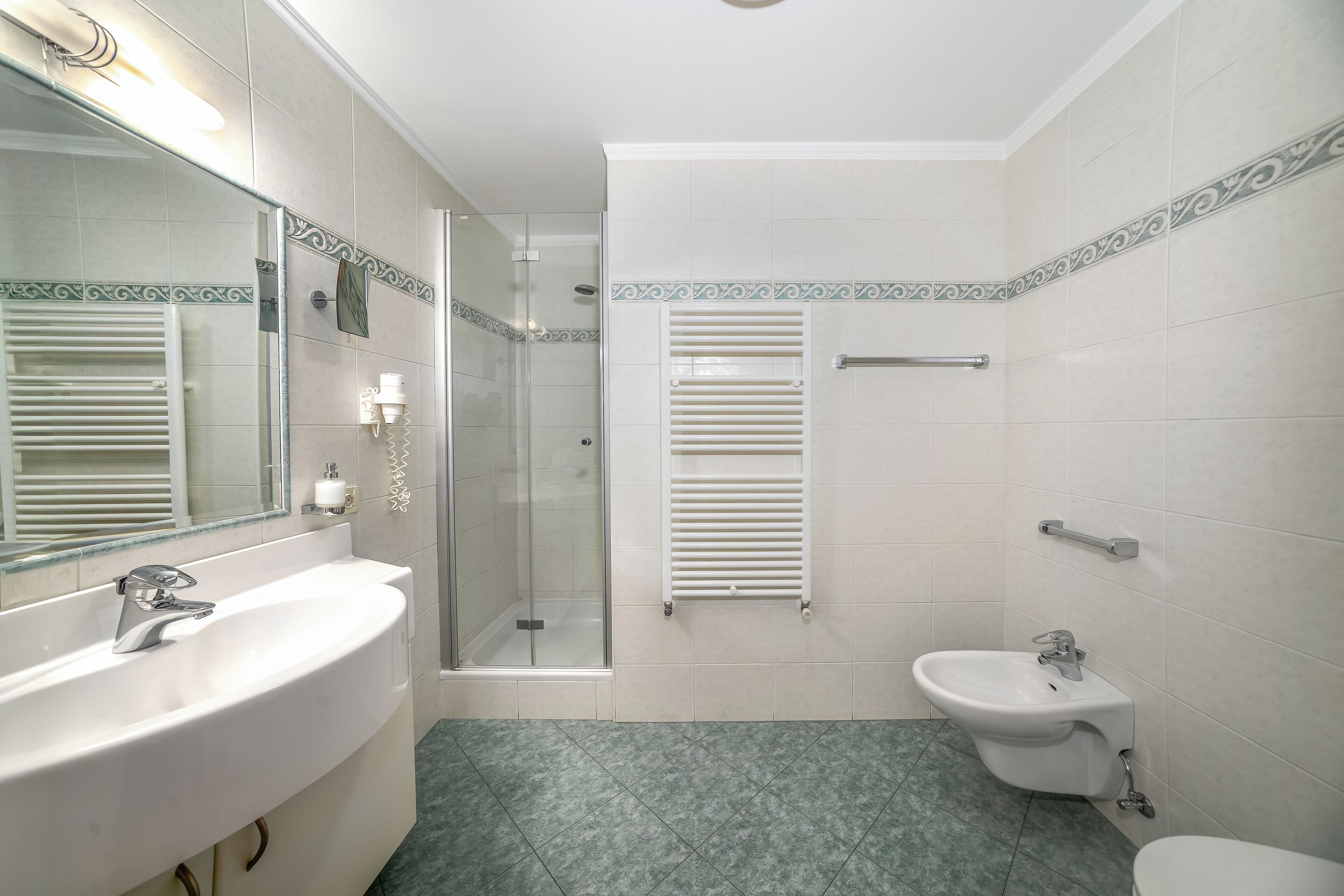 Un baño con lavamanos, bidé y ducha.