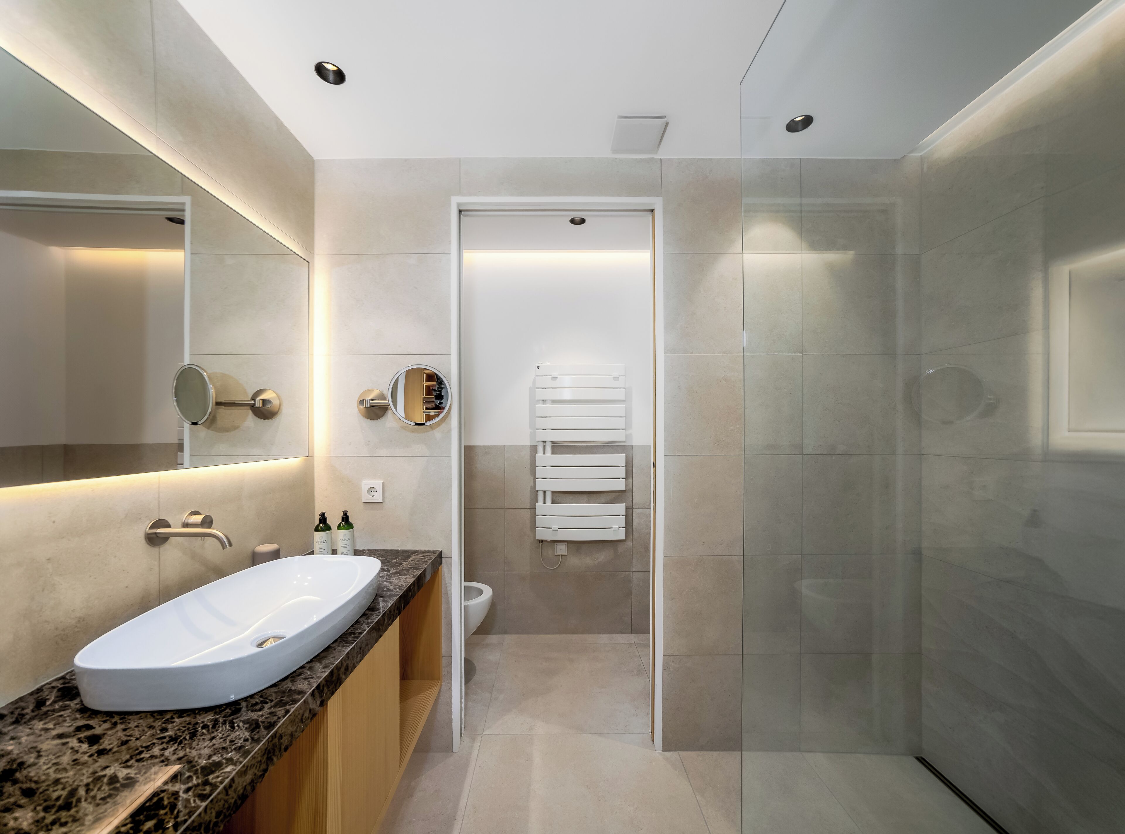 Un baño moderno con lavamanos de mármol, un espejo grande y una cabina de ducha de vidrio.