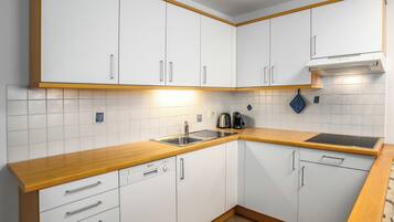 A modern kitchen with white cabinets, a wooden countertop, and a built-in dishwasher.