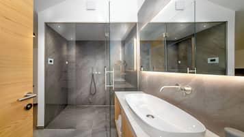 A modern bathroom with a glass-enclosed shower, a large white sink, and a wooden vanity.