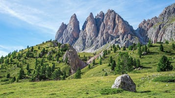A mountainous landscape with rocky peaks and green hills.