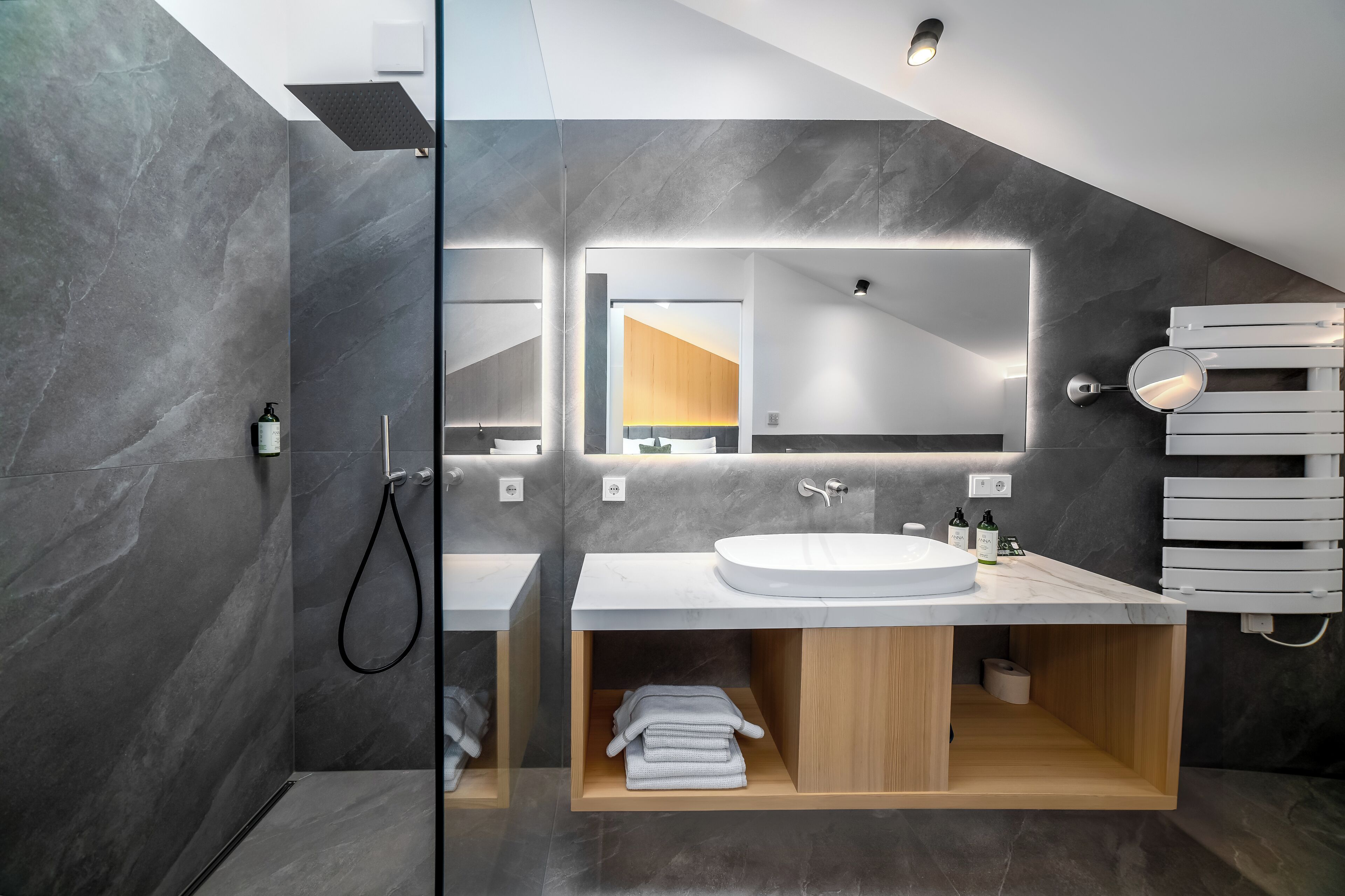 A modern bathroom with a glass-enclosed shower, a white sink, and a wooden vanity.
