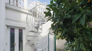 En hvid spiralopsats fører op til en balkon med en glasdør.