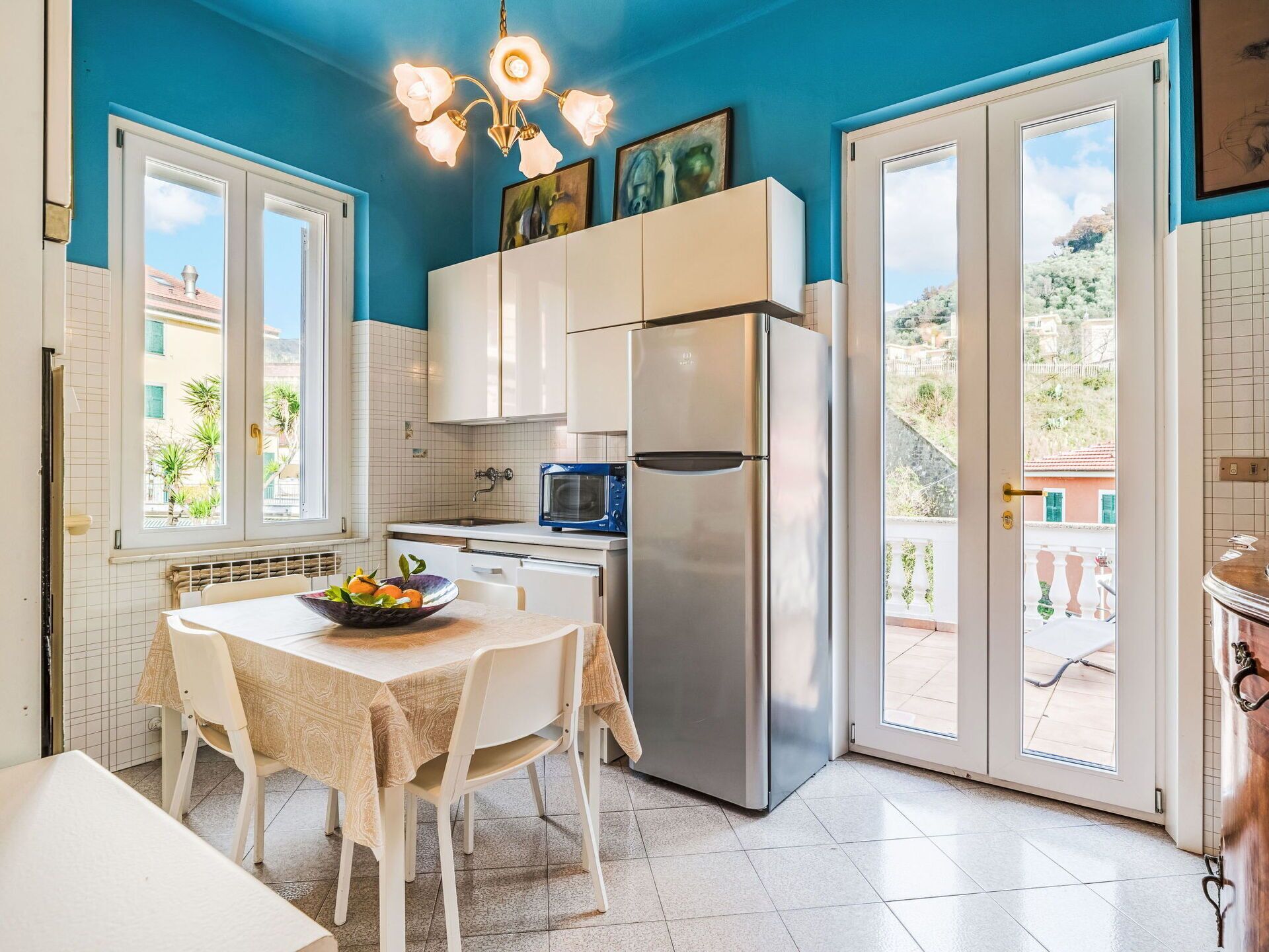 A modern kitchen with white cabinets, a stainless steel refrigerator, and a dining table set with chairs.