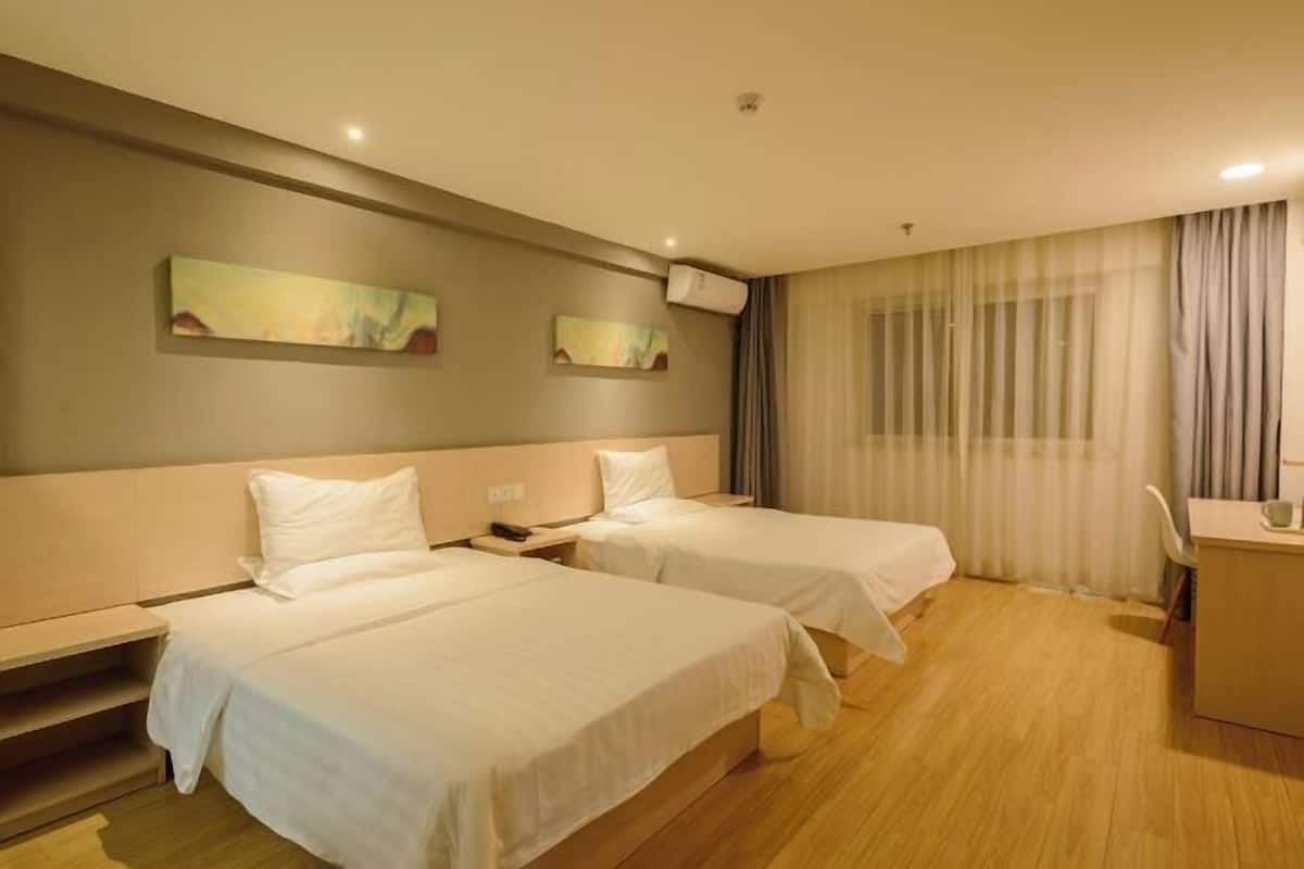 Una habitación de hotel con dos camas individuales, un escritorio y una silla.