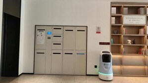 A hotel lobby with a self-service kiosk, a reception desk, and a bookshelf with books and decorative items. - HanTing Hotel (Zhengzhou Railway Station Dehua Street) (Zhengzhou)