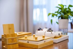Un juego de té de madera con una etiqueta en la base, una tetera blanca y una taza a juego sobre una bandeja de madera.